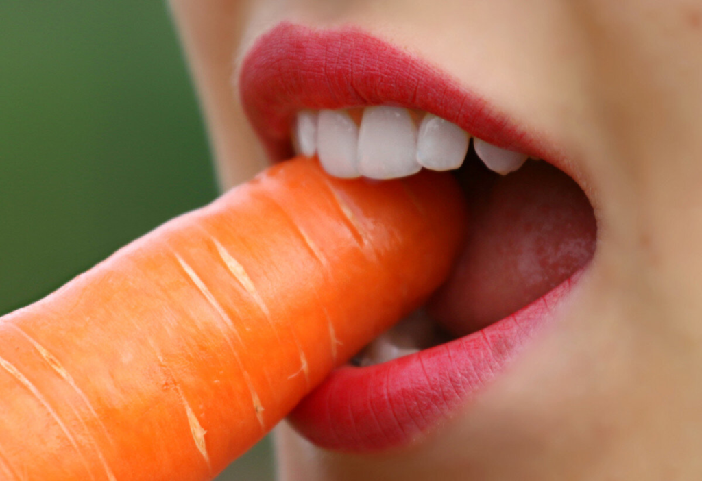 close-up of a person biting a carrot with their newly inserted dental implants