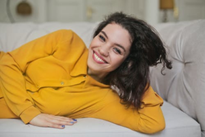 An image of a woman smiling while lying on a sofa