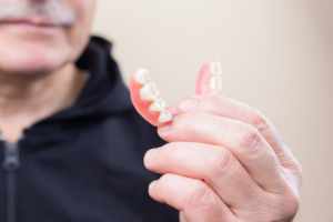 An image of a man holding dentures in his hand