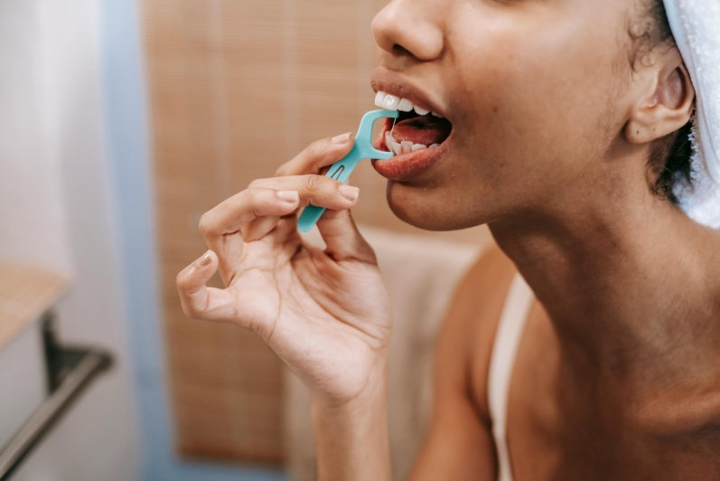 A woman cleaning her teeth with a dental flossImage File name: Dental-care