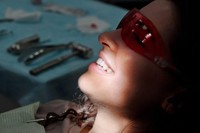 A woman wearing laser protection glasses for her crown fitting