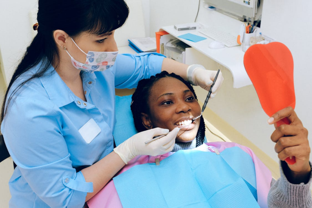 Patient and dentist seeing patient’s teeth in an orange handheld mirror