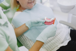 This photo shows a dentist showing a denture to a patient