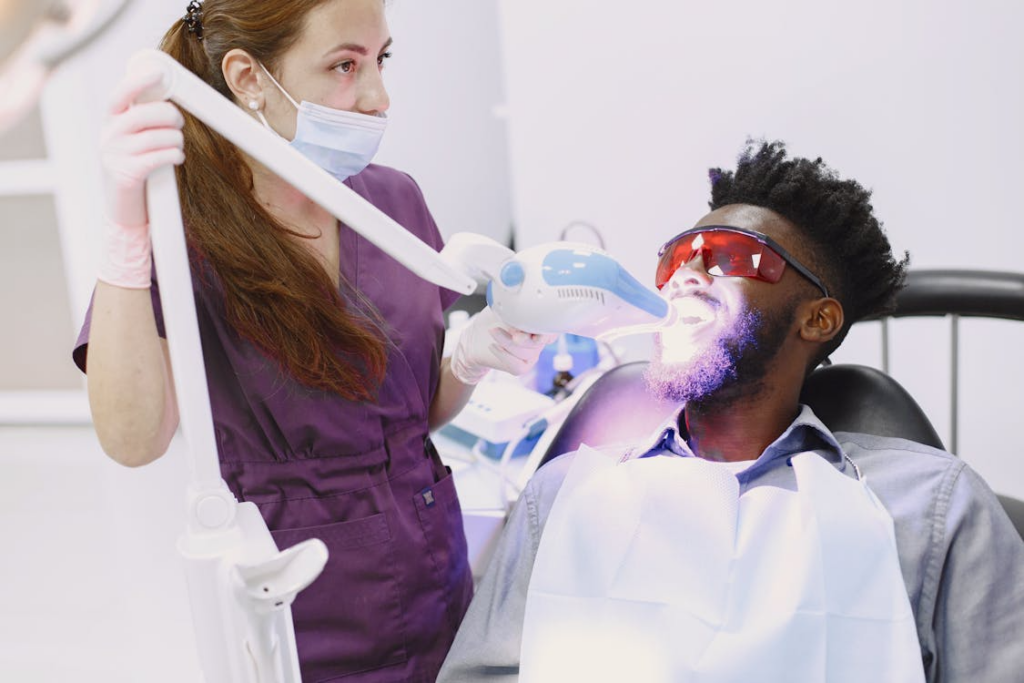 This photo shows a dentist whitening a patient’s teeth