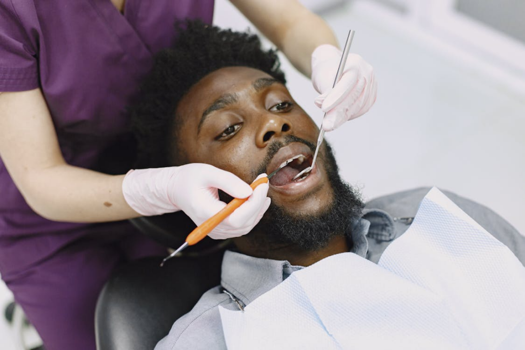 A dentist is shown examining a man's teeth during a routine dental checkup