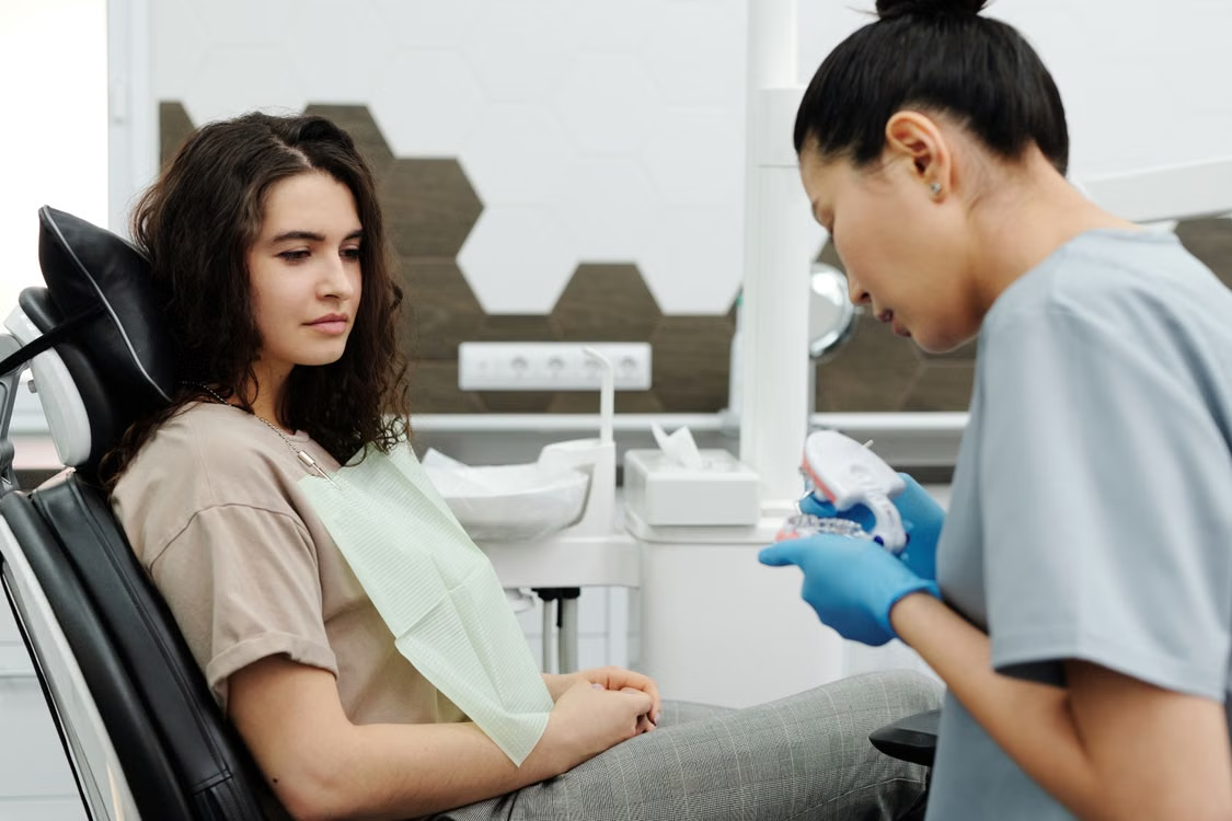a dental provider showing a denture appliance to someone in the chair