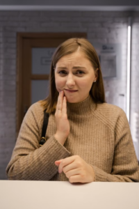 a woman holding her cheek in tooth pain