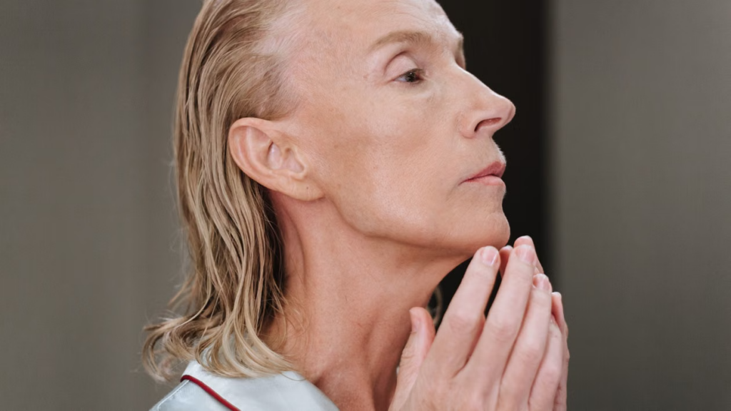 a woman in profile touching her jawline and neck