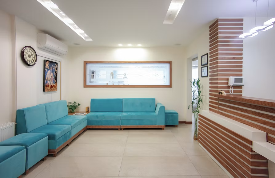 Bright and modern waiting room featuring blue sofas and a wooden reception desk