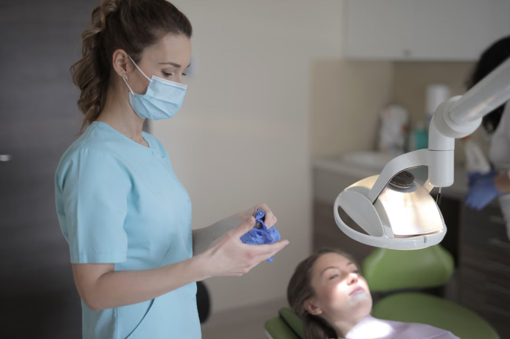 Dental professional in blue scrubs putting on gloves